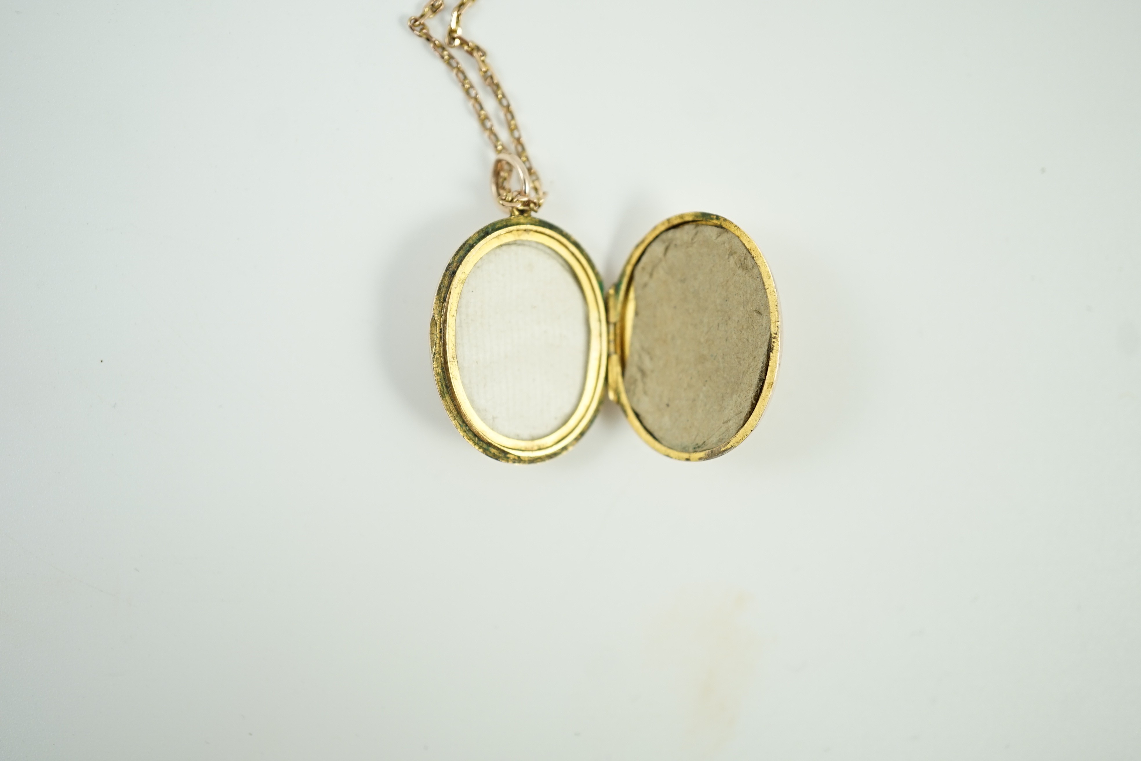 An Edwardian yellow metal and seed pearl set oval locket pendant, 25mm, on a 9ct chain, 47cm, gross weight 9.3 grams.